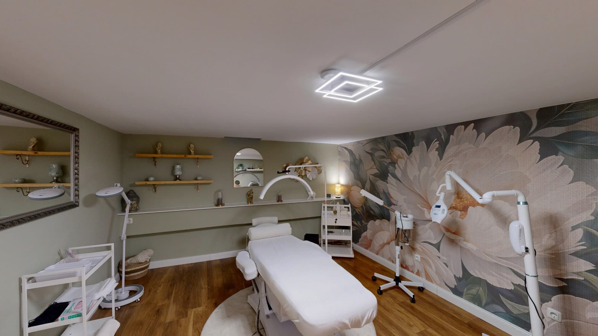 Private Beauty Room im Untergeschoss: Behandlungsliege, Lupenleuchten und großflächige Blumentapete